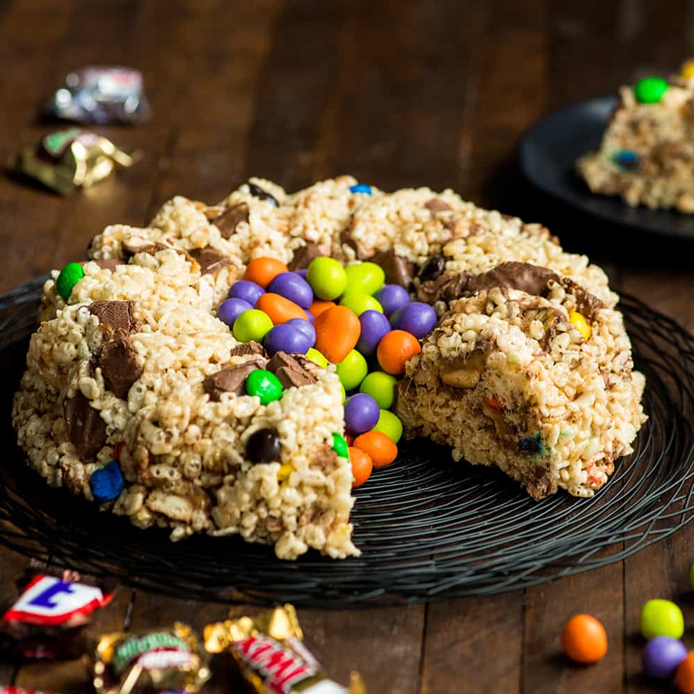 front view of a Candy-Stuffed Rice Crispy Cake on a plate with one piece removed 