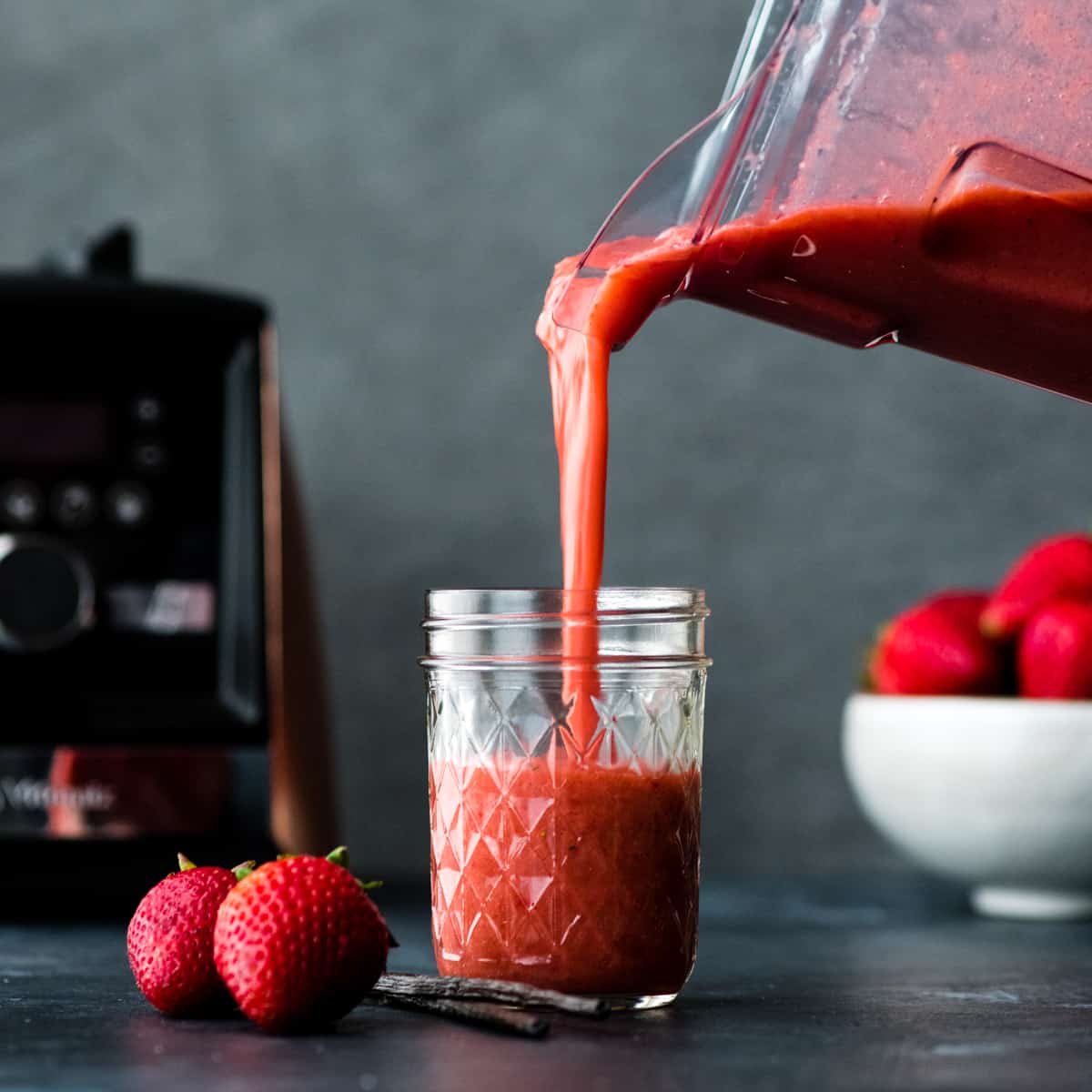 front view of Strawberry Sauce being poured out of the Vitamix container into a glass jar 