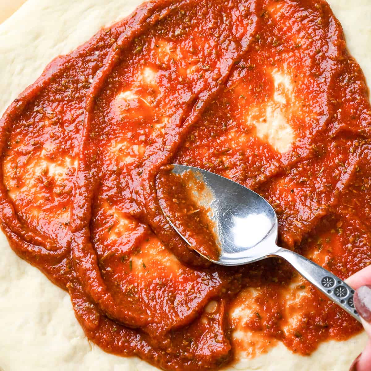 Sauce being spread onto this pizza dough recipe