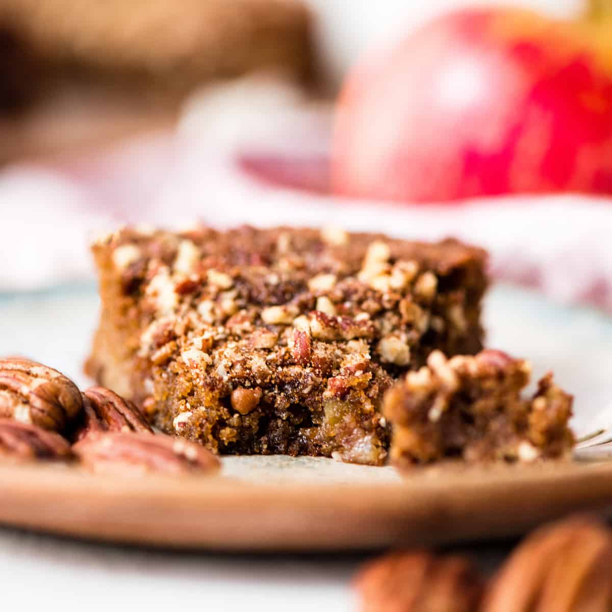 Front view of a piece of paleo gluten-free apple cake on a plate with a bite taken out of it