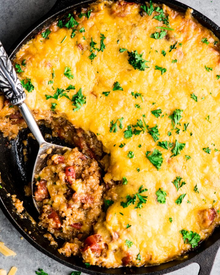 up close overhead view of a spoon taking a scoop of Baked Quinoa Casserole out of the cast iron skillet