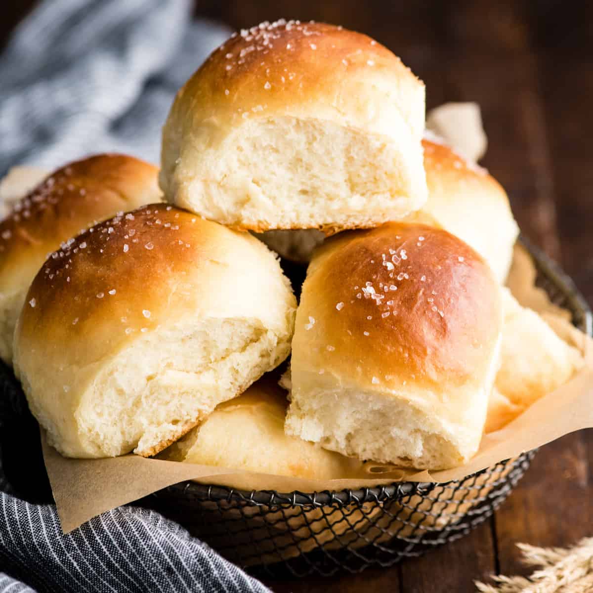 front view of 6 homemade Dinner Rolls stacked on each other in a basket after baking