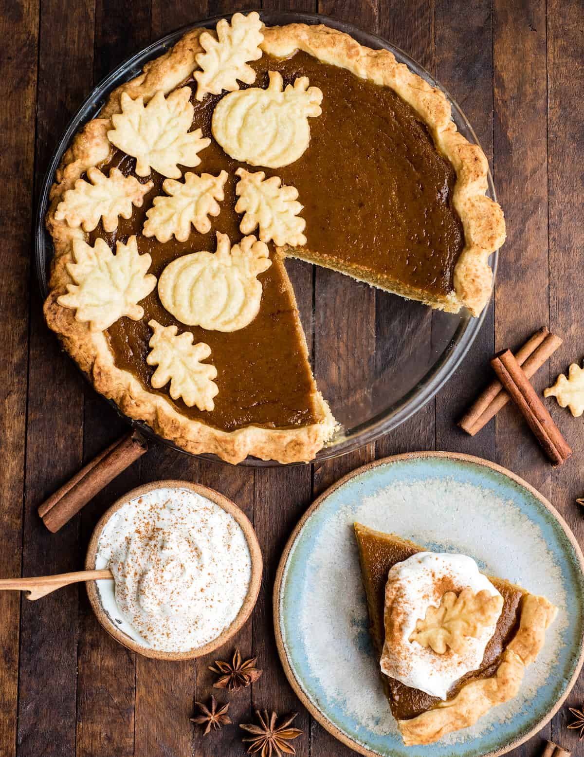 overhead view of dairy-free pumpkin pie in a glass pie dish with one piece cut out and on a plate next to the pie dish