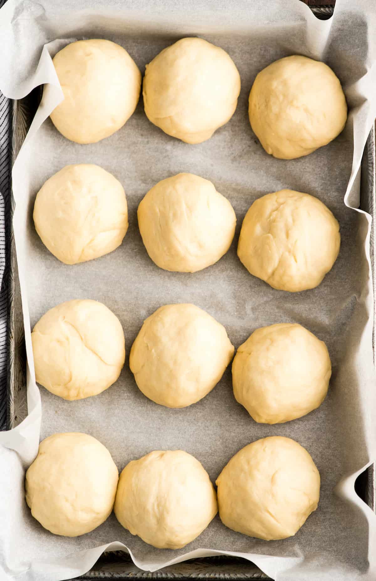 overhead view of a pan of 12 dinner rolls dough balls before rising