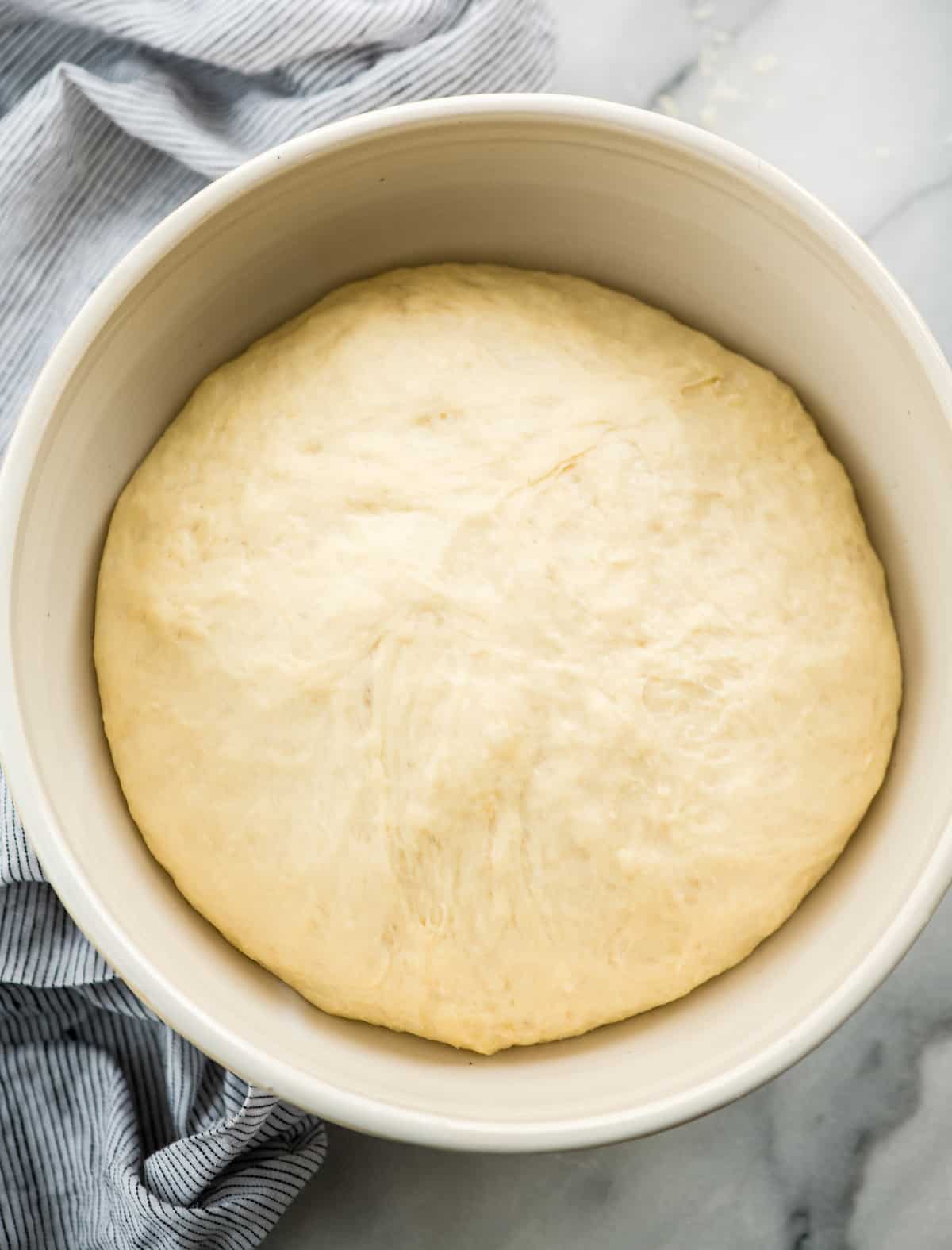 overhead view of risen dinner roll dough in a bowl 