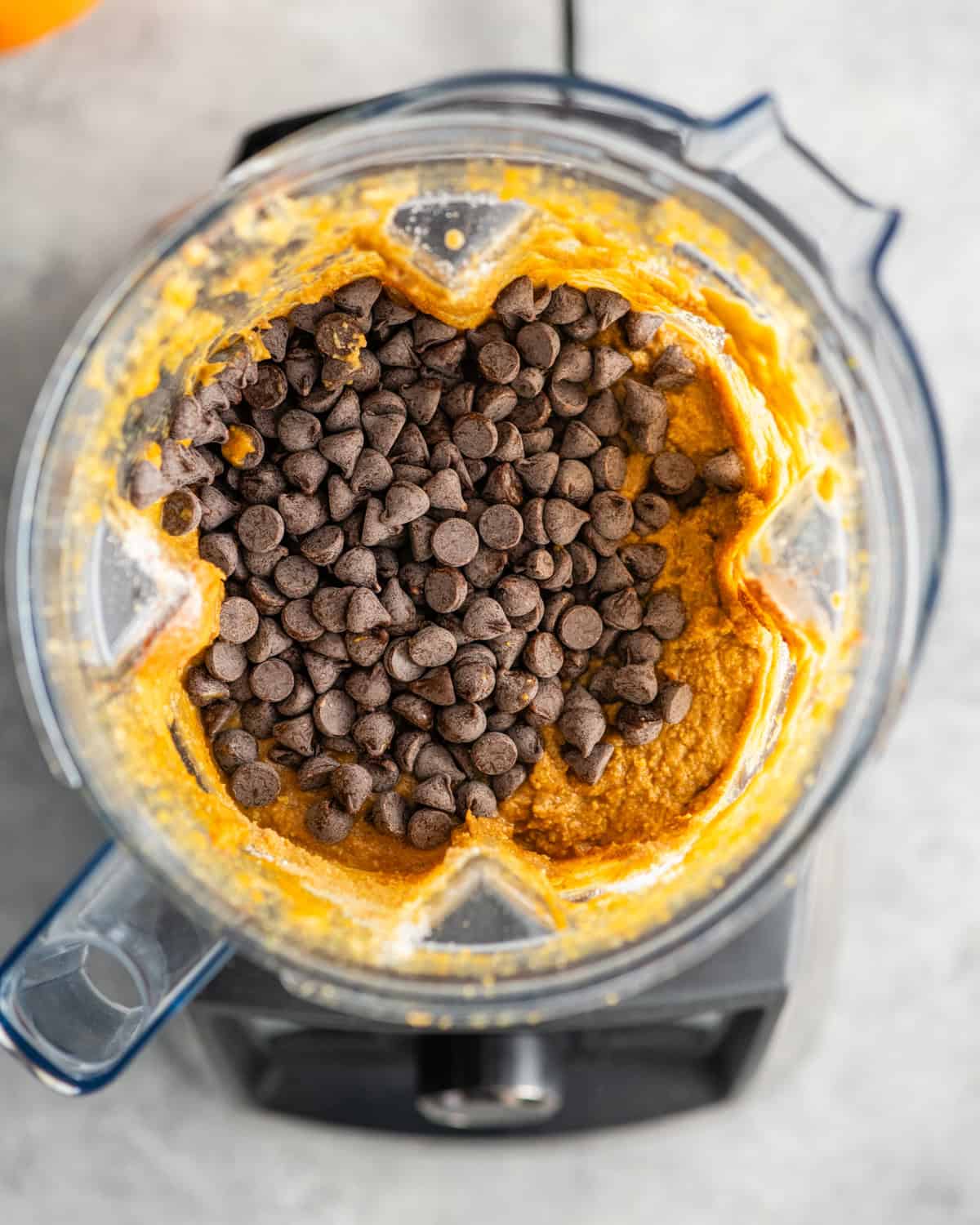 adding chocolate chips to Paleo Pumpkin Zucchini Muffins batter in a blending container