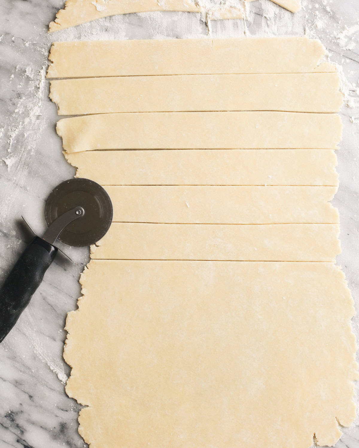butter pie crust rolled out and being cut to make a lattice top