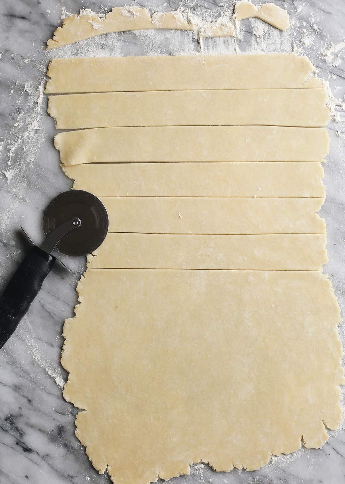 butter pie crust rolled out and being cut to make a lattice top