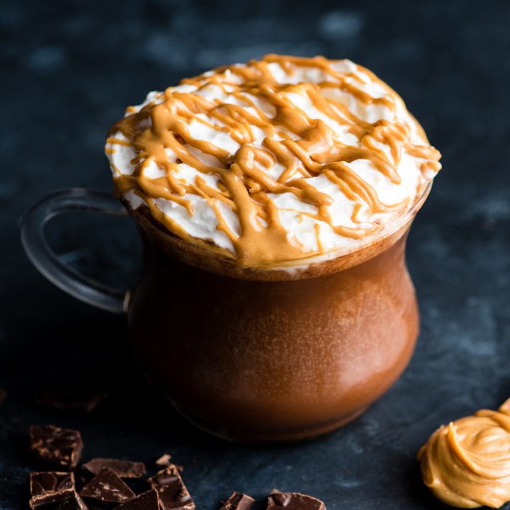 overhead view of Peanut Butter Hot Chocolate in a glass mug with whipped cream and a drizzle of peanut butter on top