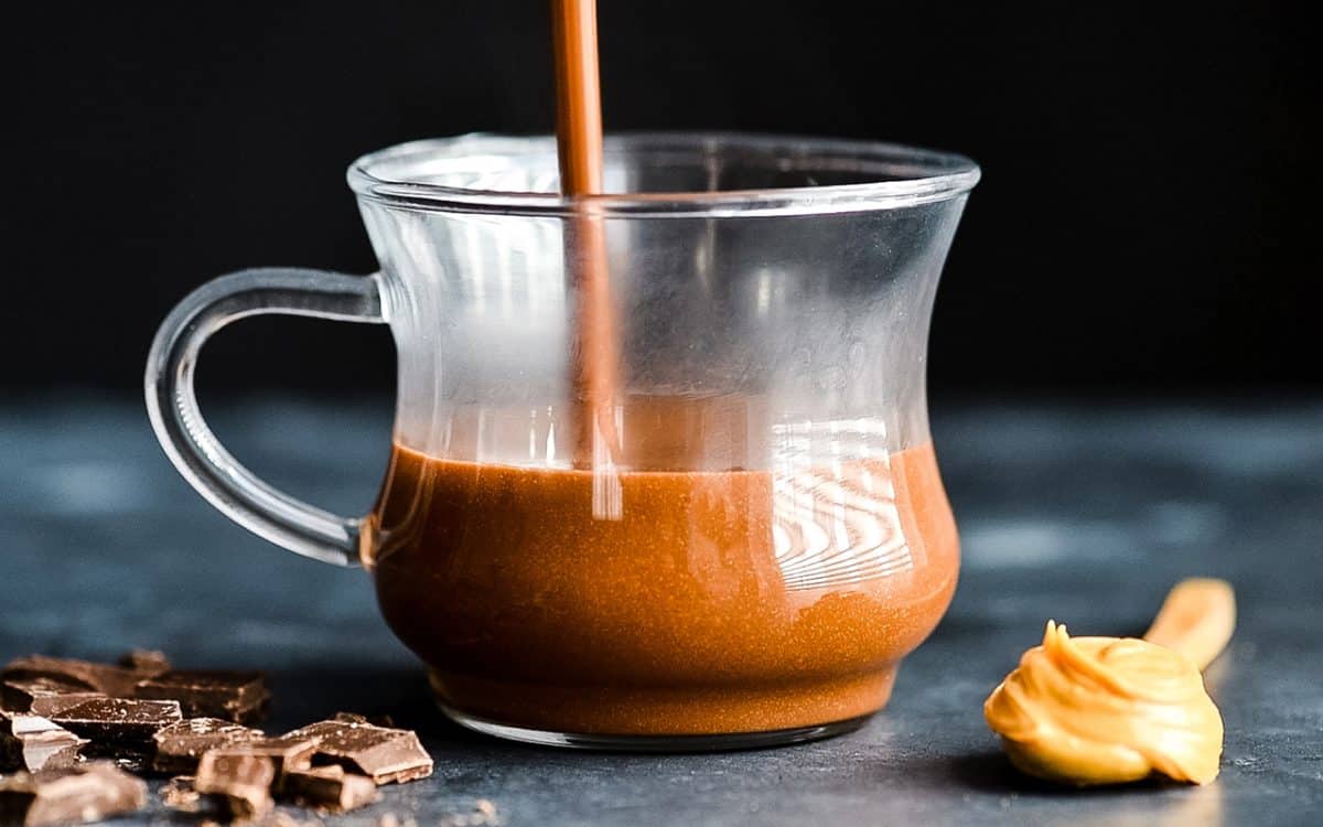 peanut butter hot chocolate being poured into a glass mug