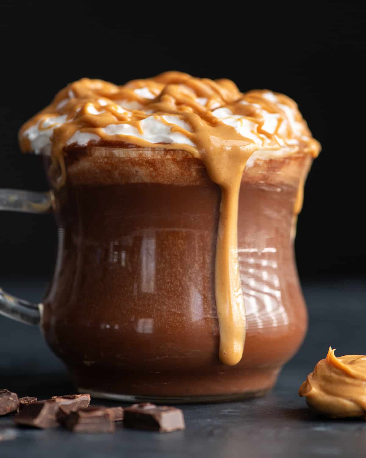 front view of a mug of peanut butter hot chocolate with whipped cream and peanut butter drizzle