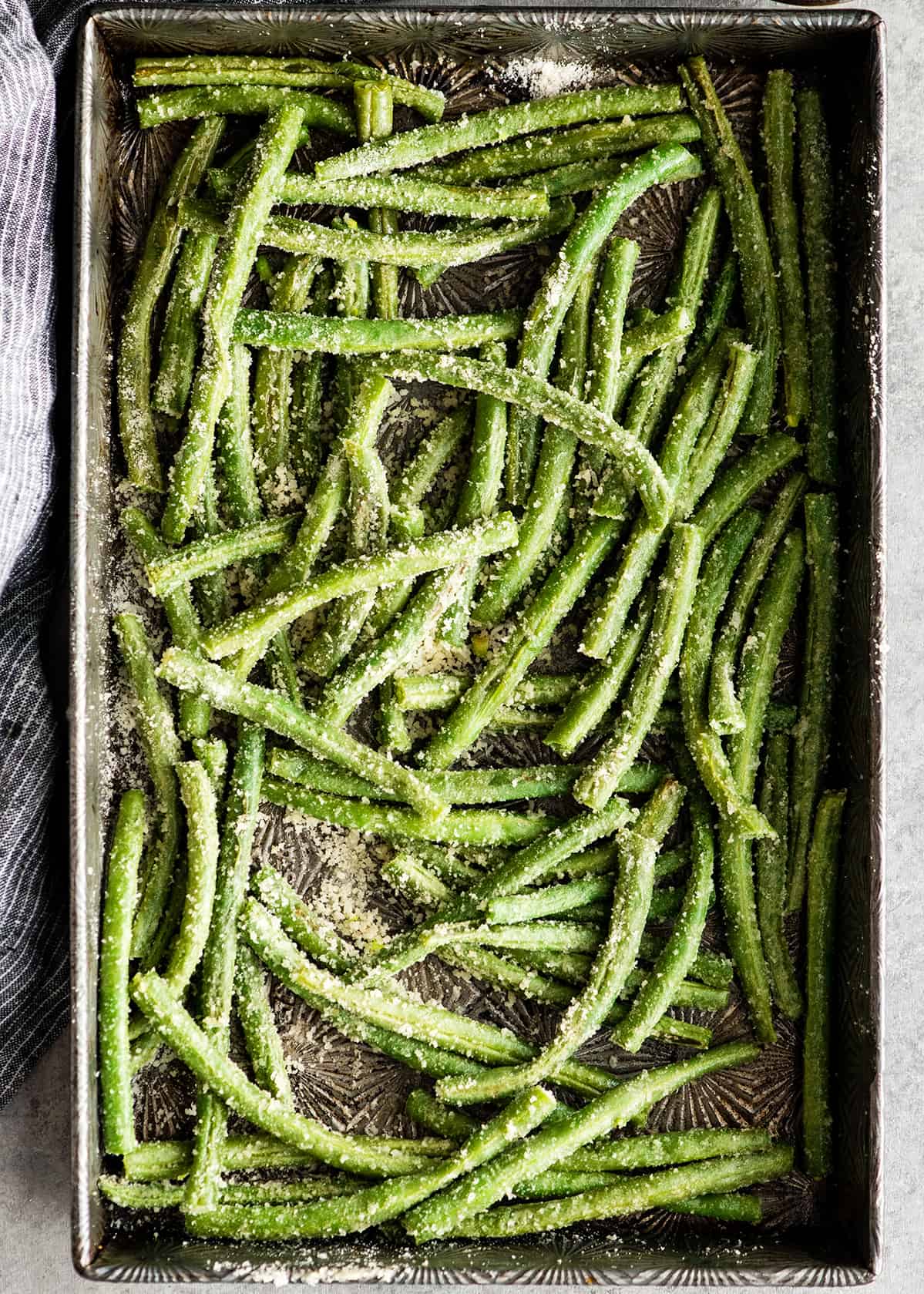 overhead photo of Roasted Parmesan Green Beans on a baking sheet before the second roast