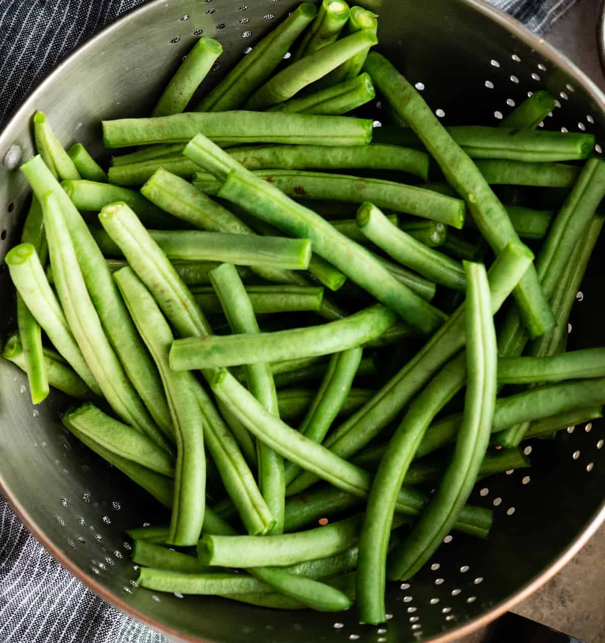 overhead photo of fresh green beans in a colander to be washed