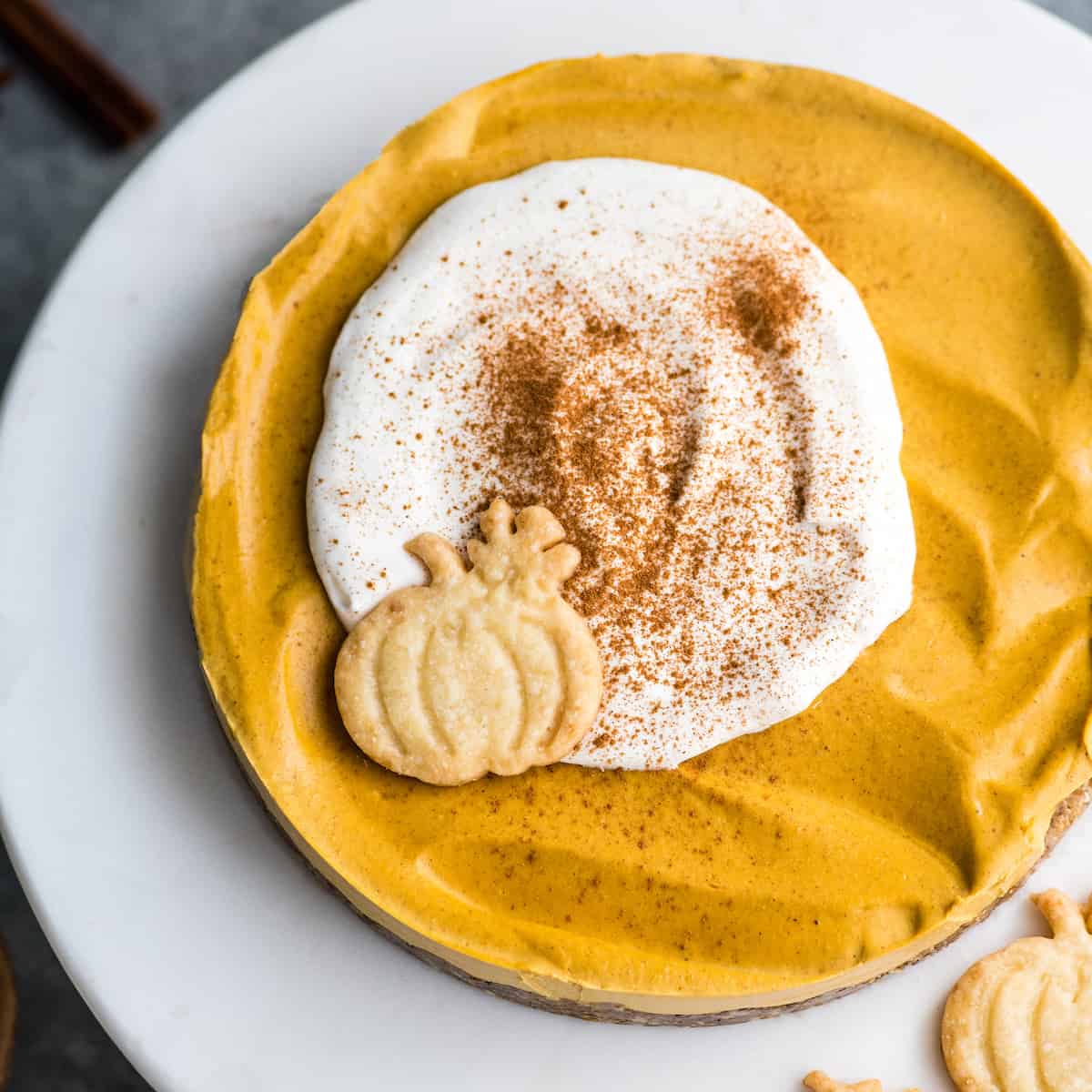 overhead view of this no-bake vegan pumpkin cheesecake recipe with whipped cream on top and a sprinkle of cinnamon