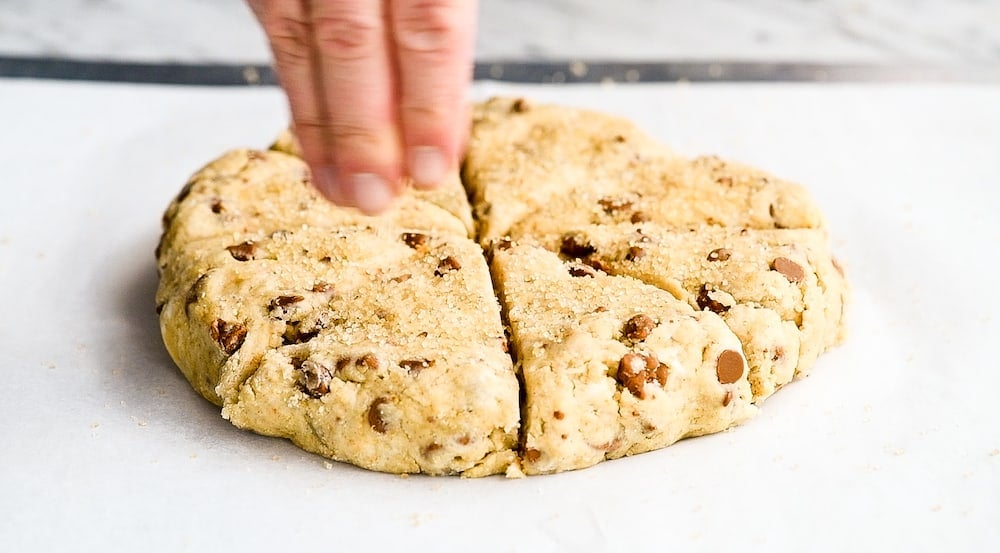 front view of hands sprinkling sugar onto Cinnamon Scone dough