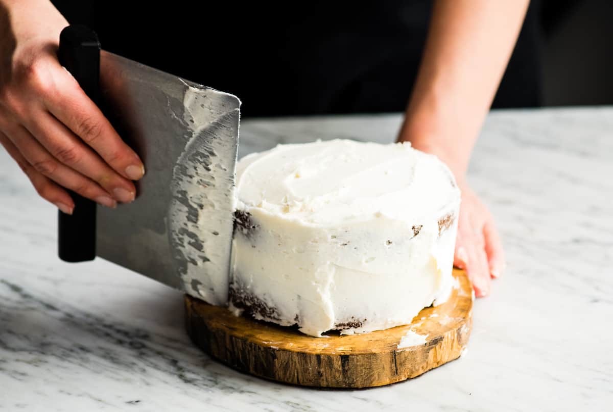 Front view of a person frosting a 6" round cake with white frosting to make a Birthday Cake for Jesus