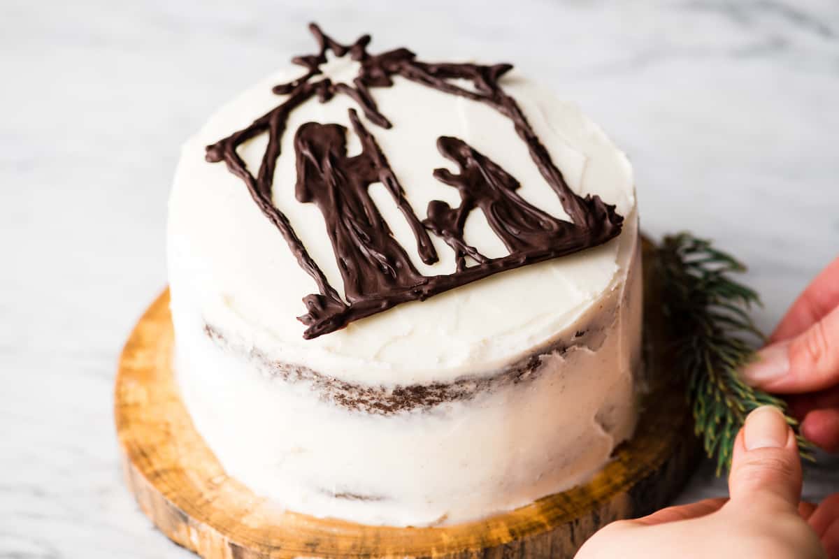 nativity cake on a wooden circle with hands situation pine branches around it 