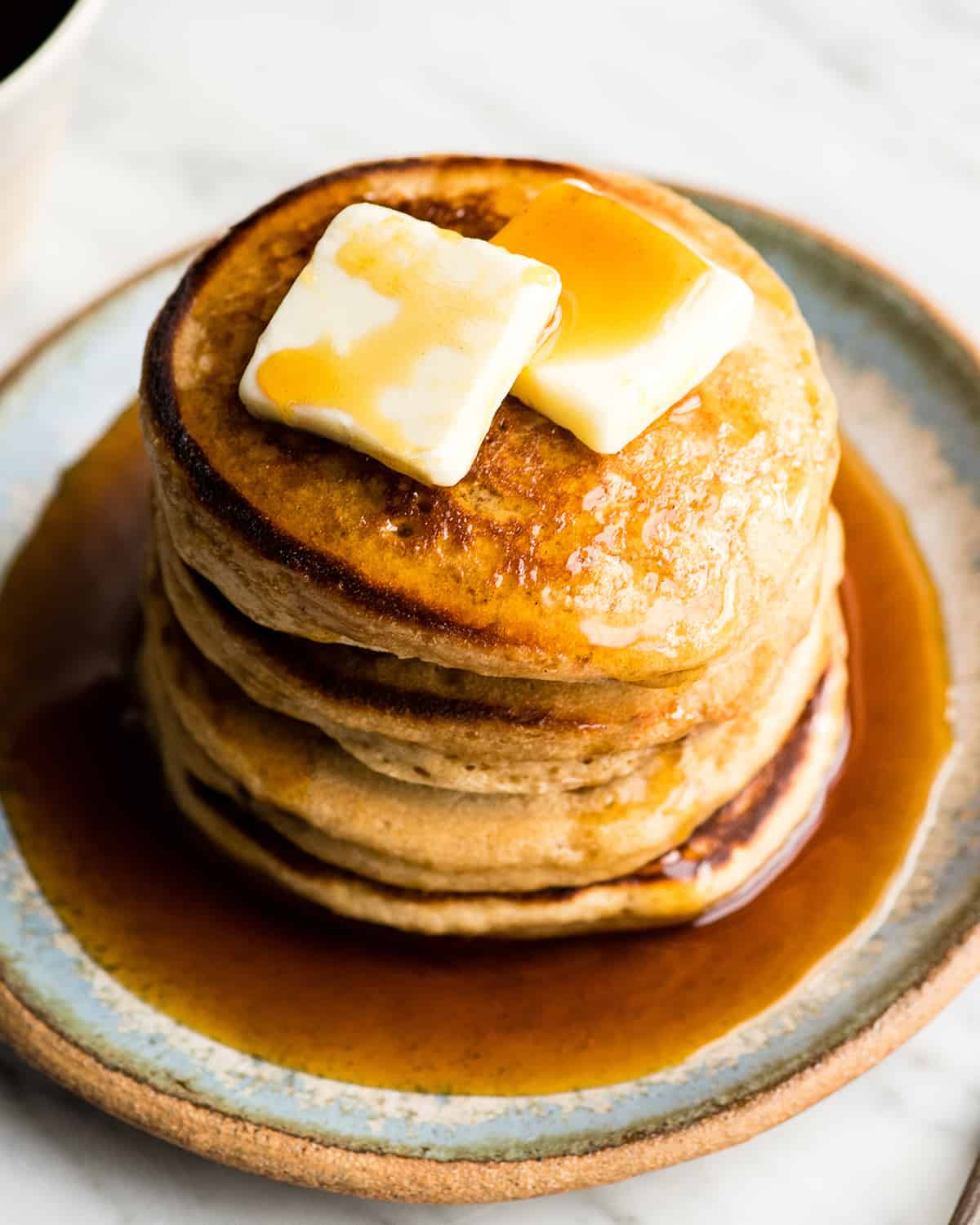 a stack of 4 greek yogurt pancakes with butter and syrup