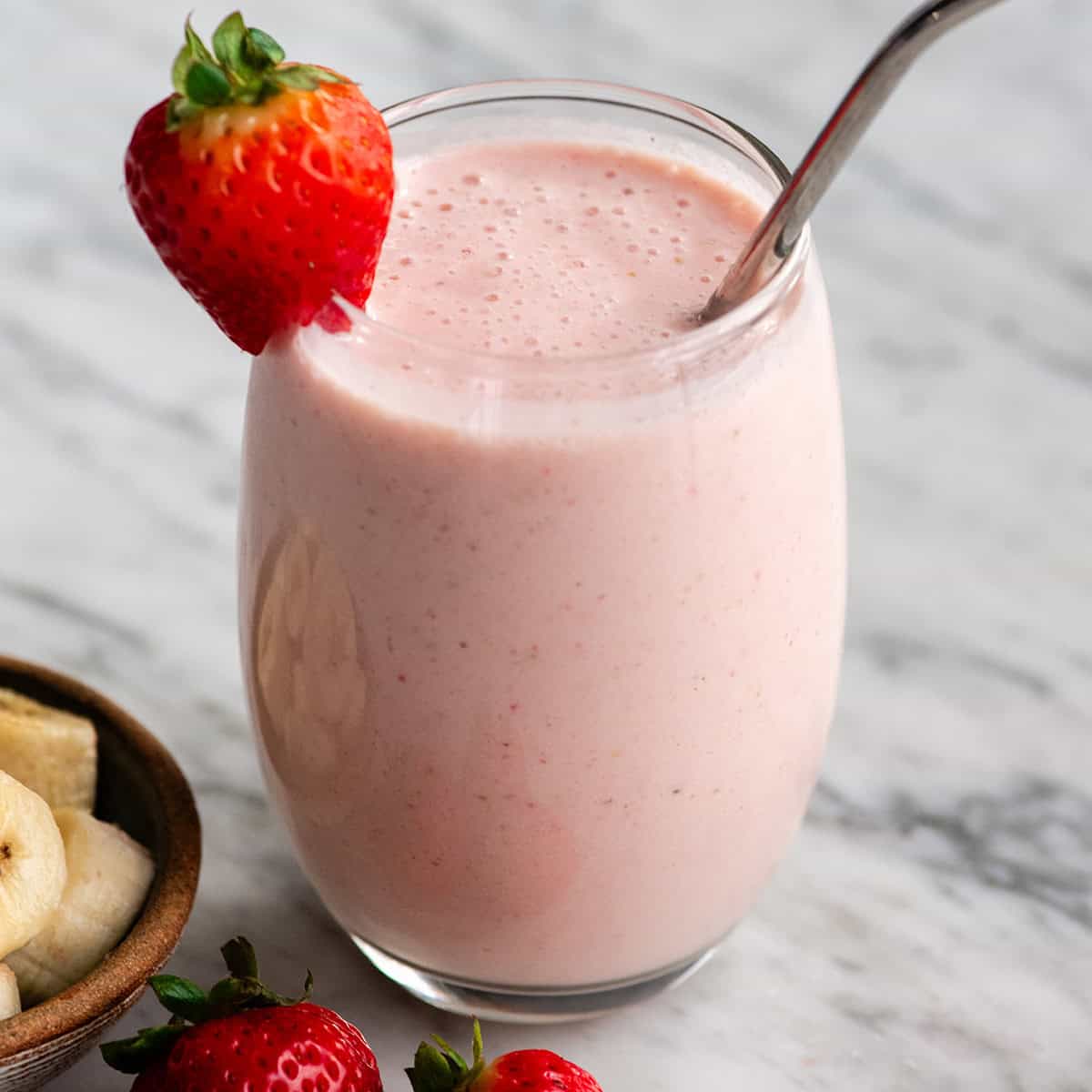 a glass of strawberry banana smoothie with straw