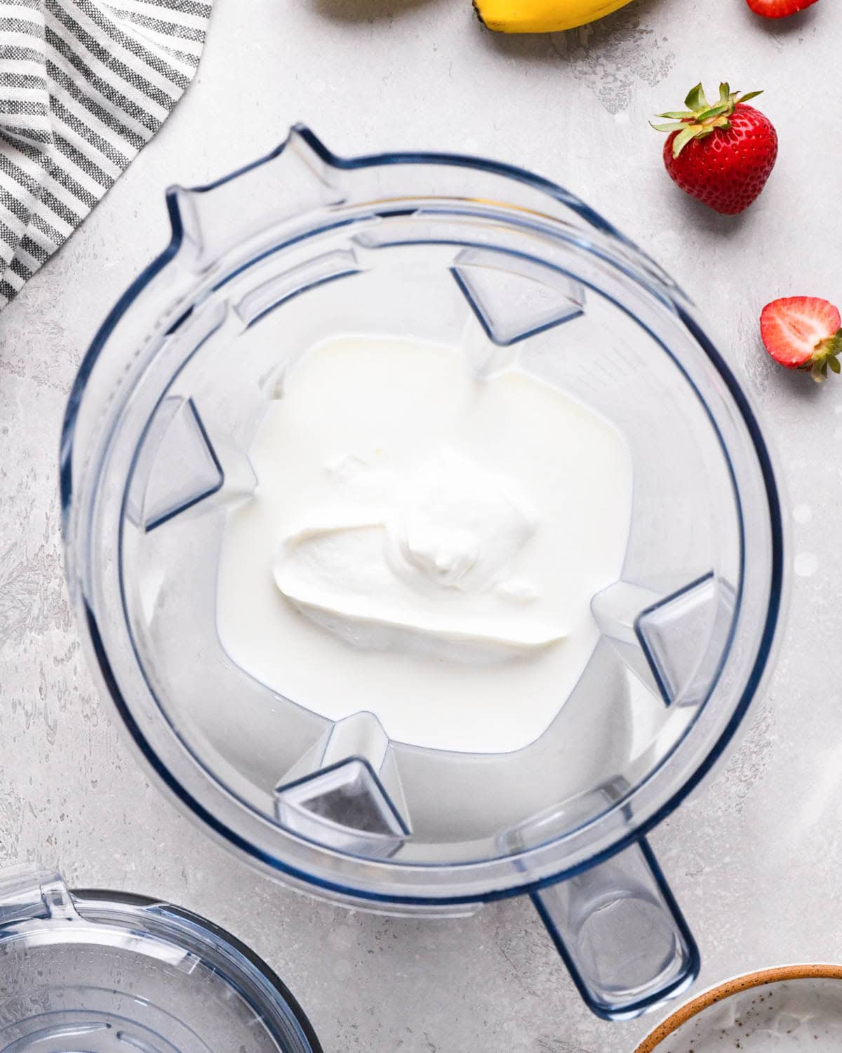 how to make a strawberry banana smoothie - milk and greek yogurt in a blending container before blending