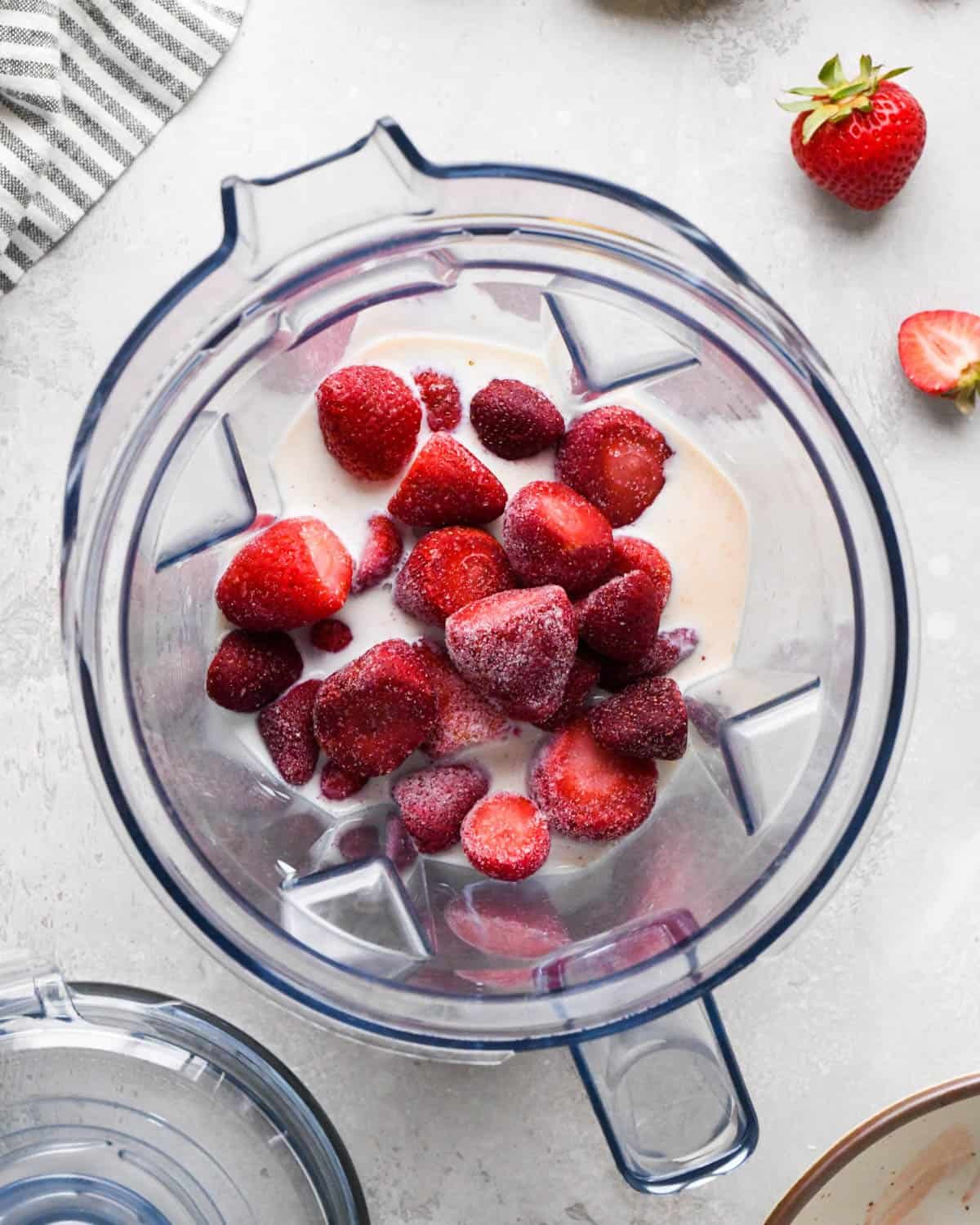 how to make a strawberry banana smoothie - milk, greek yogurt, honey, vanilla and strawberries in a blending container before blending