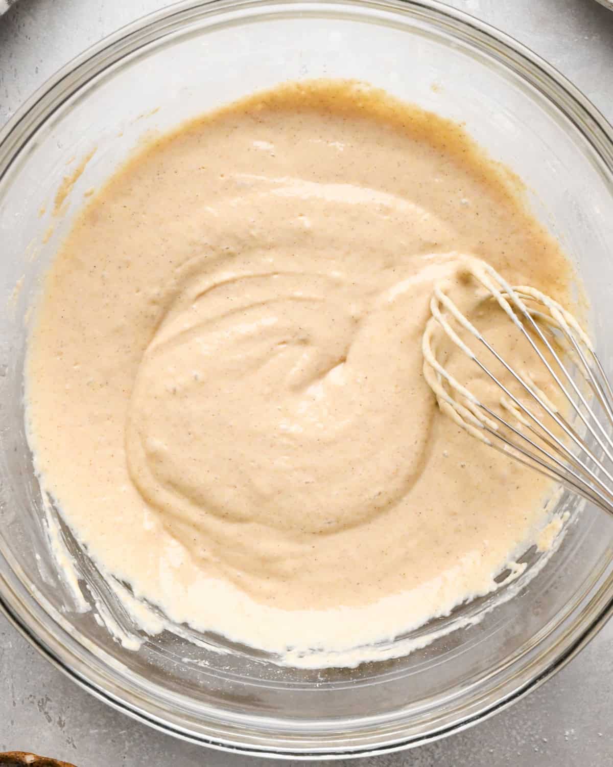 greek yogurt pancakes batter in a glass bowl with a wire whisk on a gray surface 