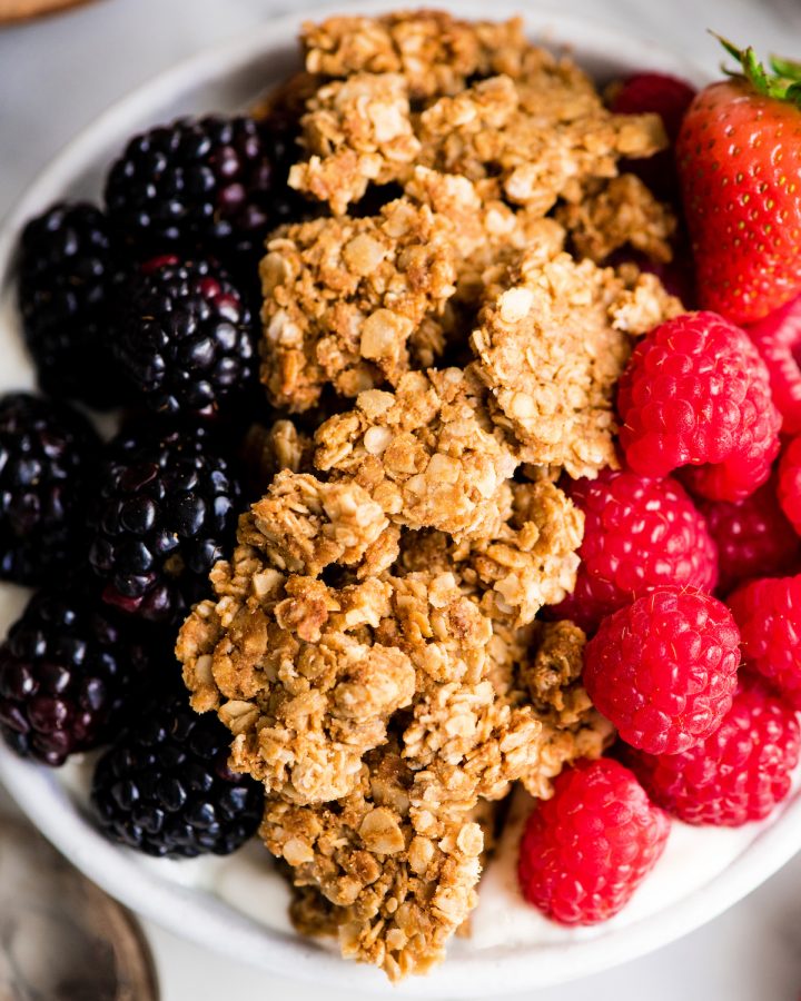 Up close overhead view of peanut butter granola in a bowl of yogurt and berries