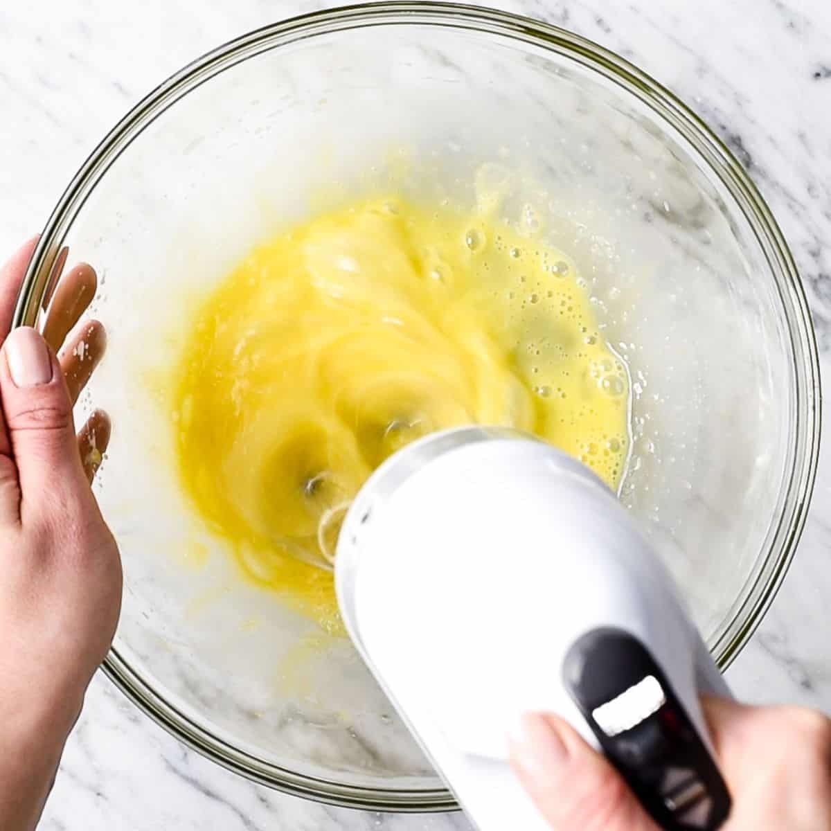 How to Make Flourless Brownies - eggs being beaten with a hand mixer in a glass bowl