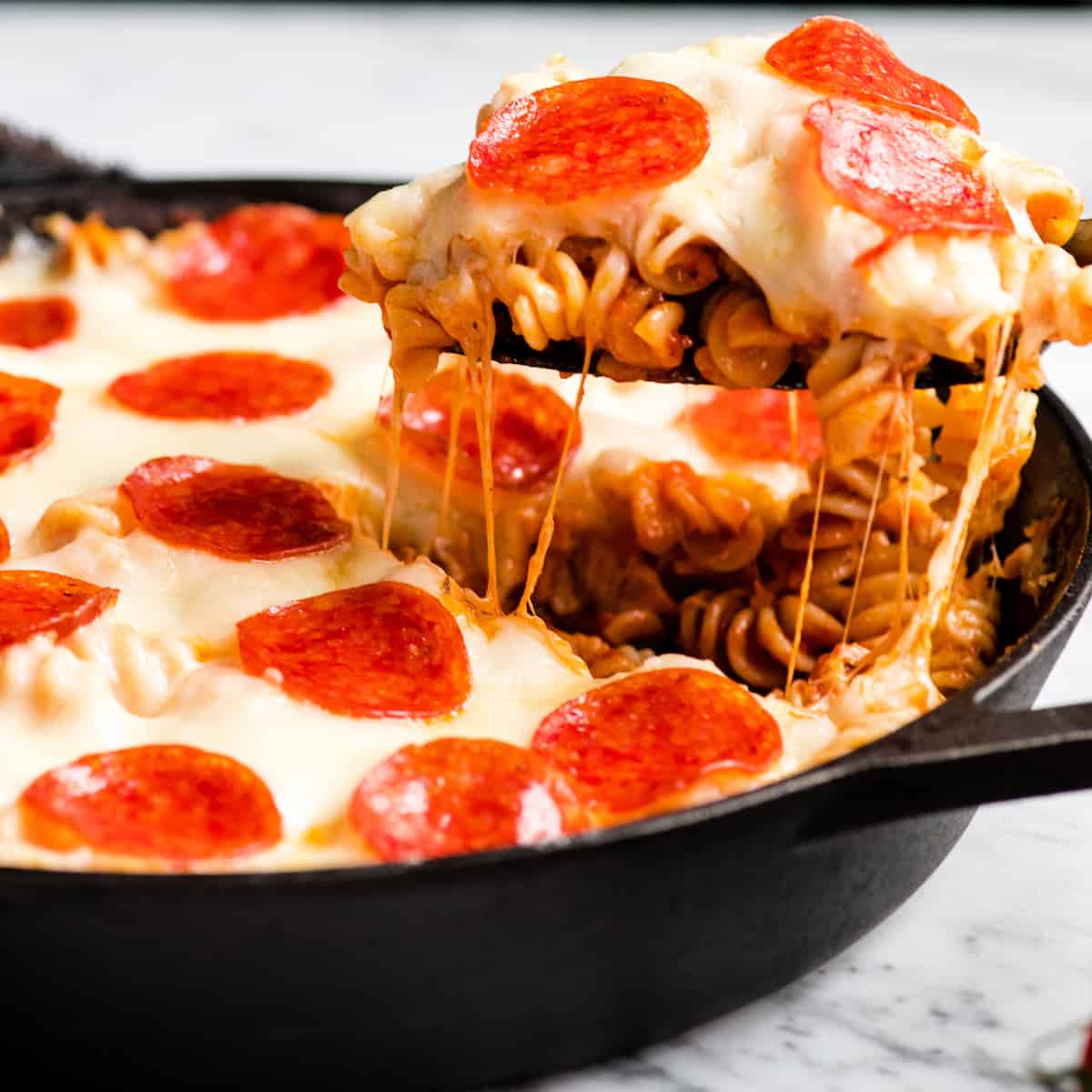 front view of a piece of pizza casserole being pulled from the pan as strings of cheese pull off too