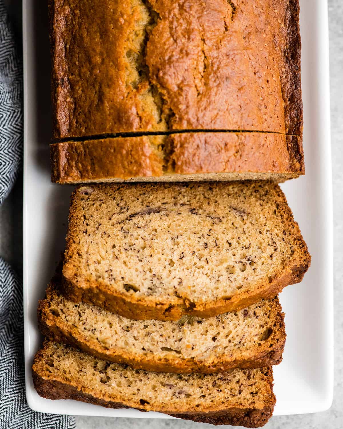 Overhead view of a loaf of banana bread with three slices cut out of it laying flat on a plate