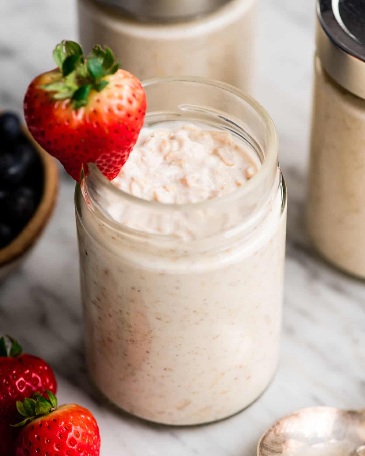 a jar of Yogurt Overnight Oats with the lid removed and a strawberry on the rim