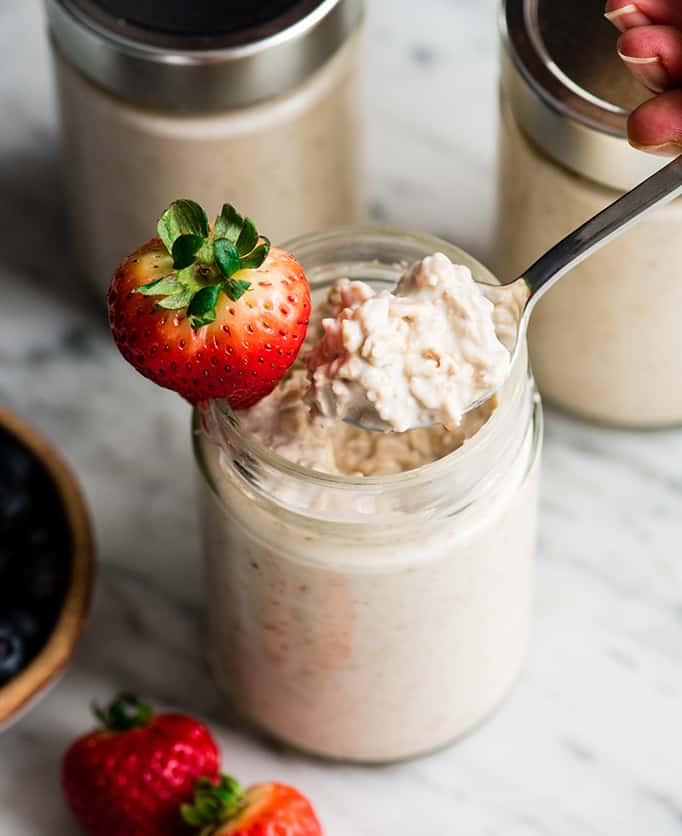 aanzicht van een lepel die een schep yoghurt overnight oats uit een potje neemt