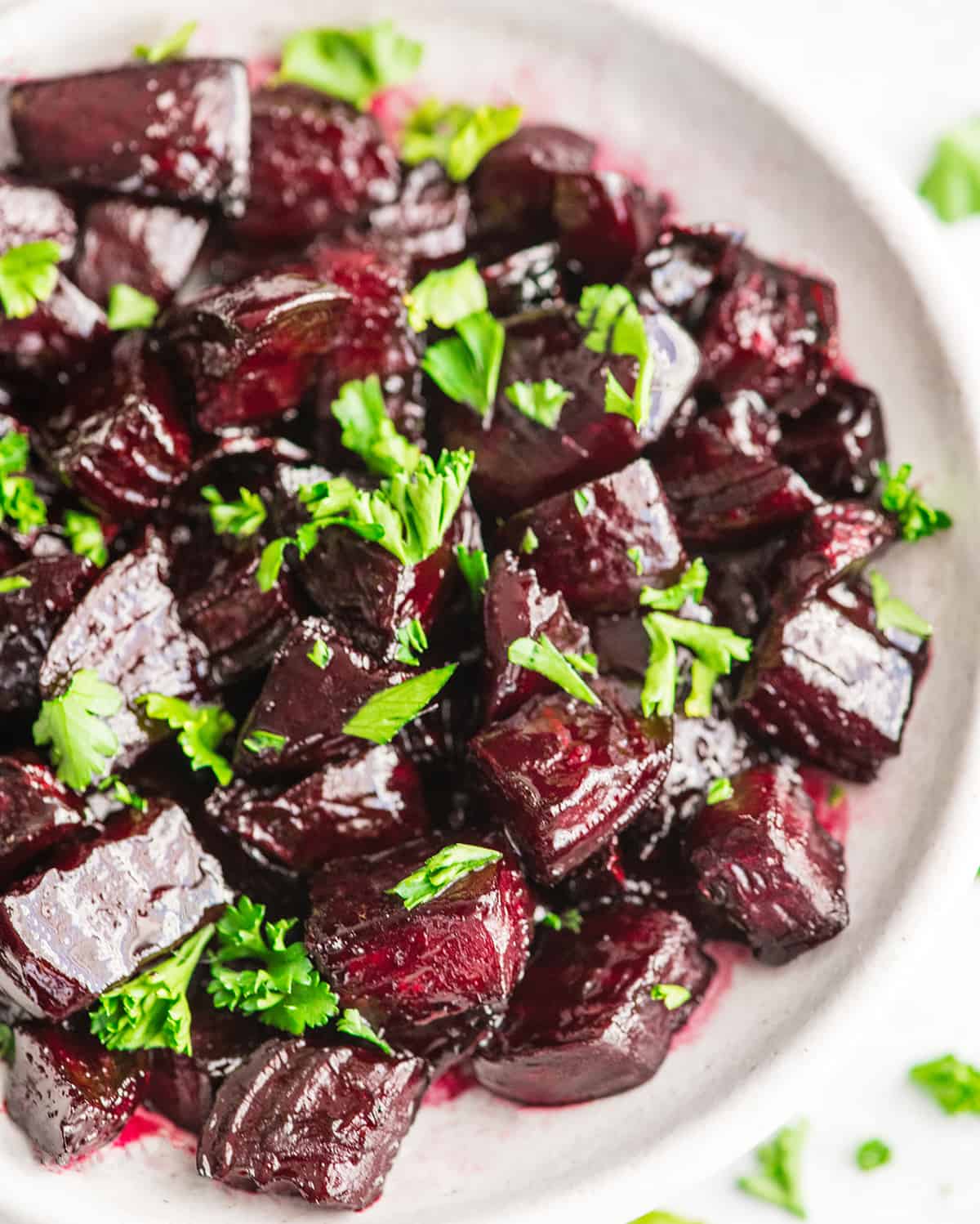 Overhead view of a bowl of balsamic roasted beets garnished with beet greens