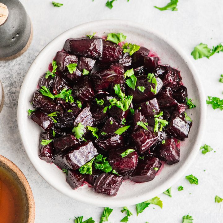 overhead photo of a bowl of Balsamic Roasted Beets garnished with greens