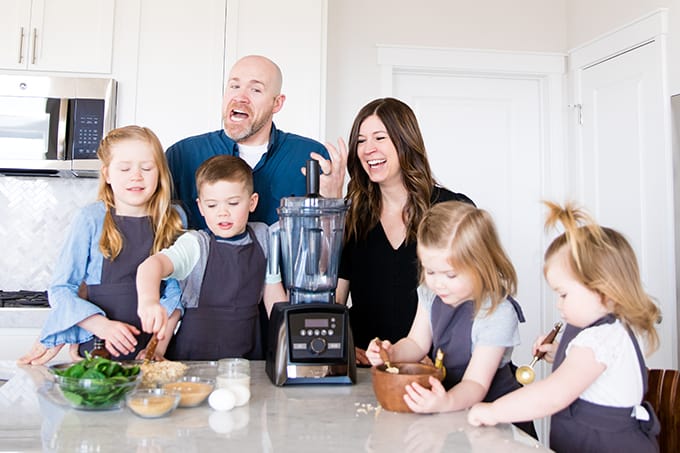 Front view of a mom and dad and their four kids cooking with kids