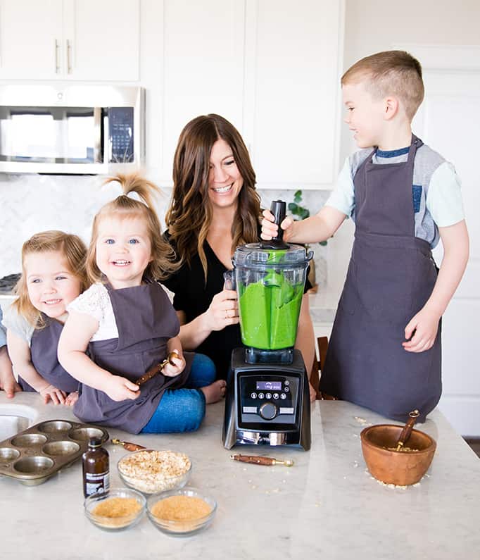 Front view of a mom and her four kids blending in a blender while she's Cooking with Kids