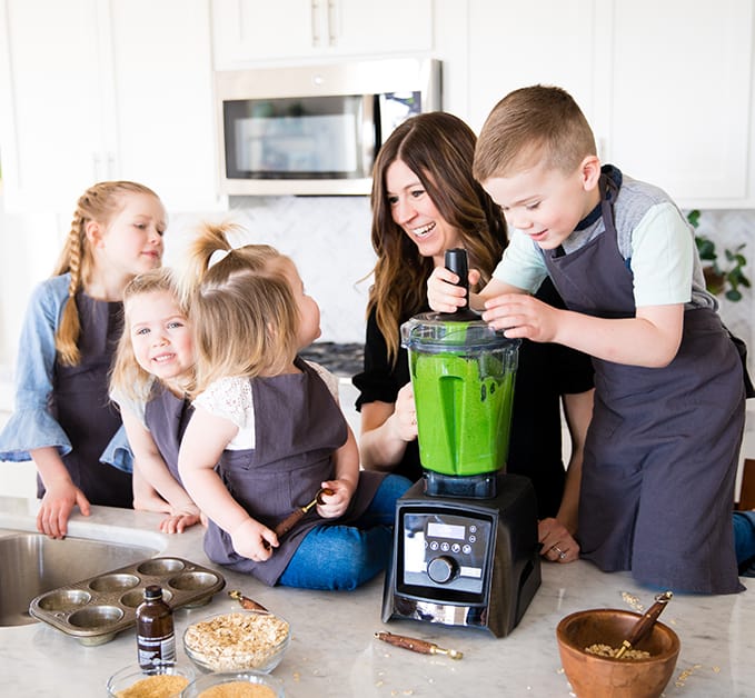 Front view of a mom and her four kids blending in a blender while she's Cooking with Kids