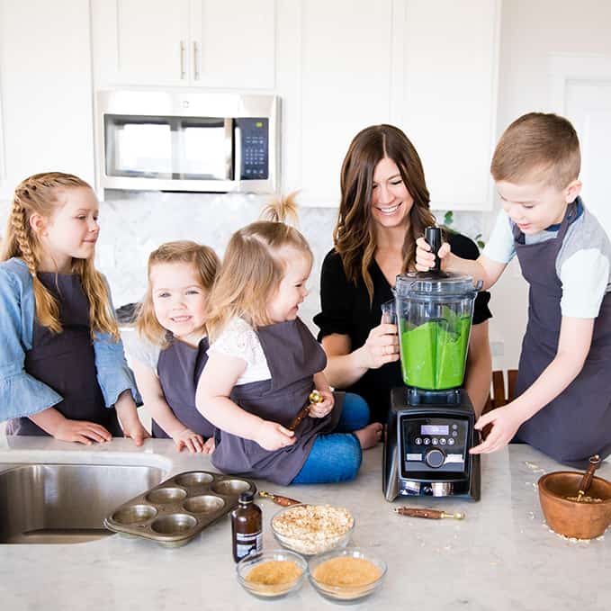 Front view of a mom and her four kids blending in a blender while she's Cooking with Kids