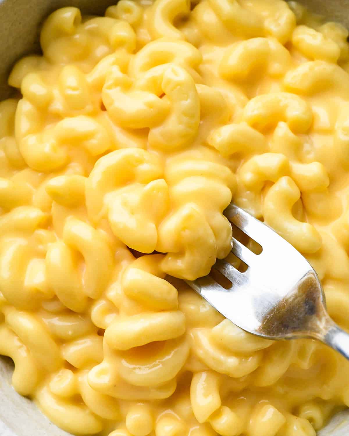 a fork taking a bite of mac and cheese in a bowl