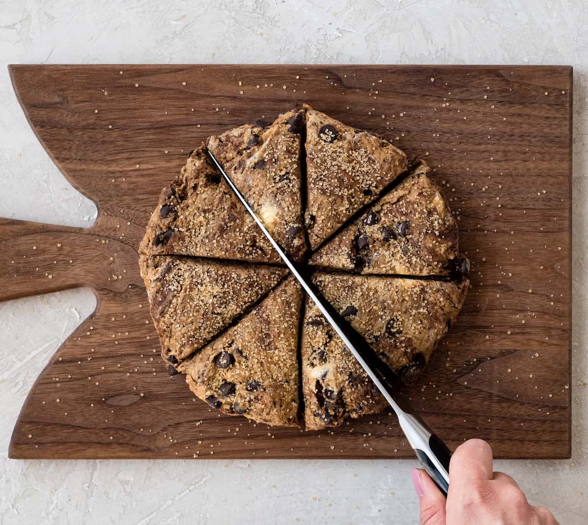 Overhead view of a hand using a large knife to cut this Mocha Chocolate Scones recipe into eight scones 