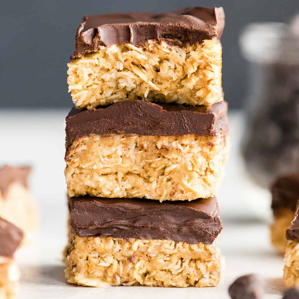 front view of a stack of three No-Bake Oatmeal Bars with Peanut Butter & Coconut, the top one has a bite taken out of it