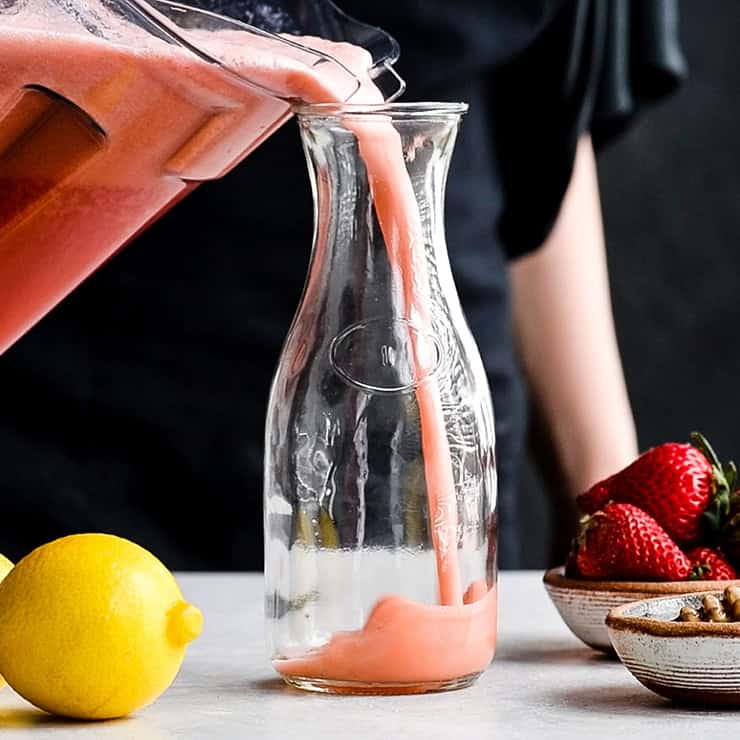 Homemade Strawberry Lemonade being poured into a glass pitcher
