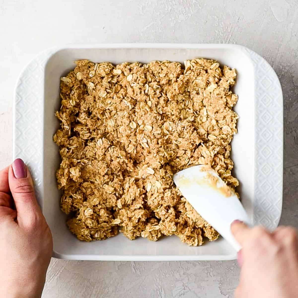 No Bake Oatmeal Bars being pressed into a baking dish