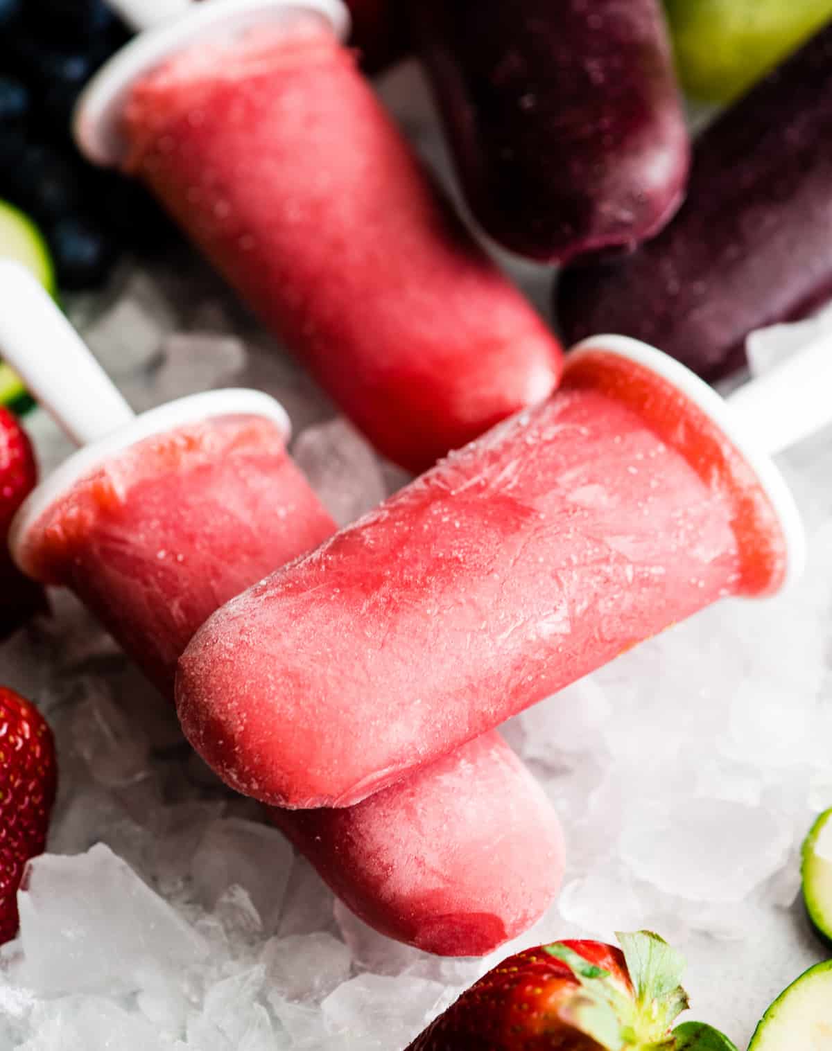 two red homemade popsicles sitting on top of each other over ice
