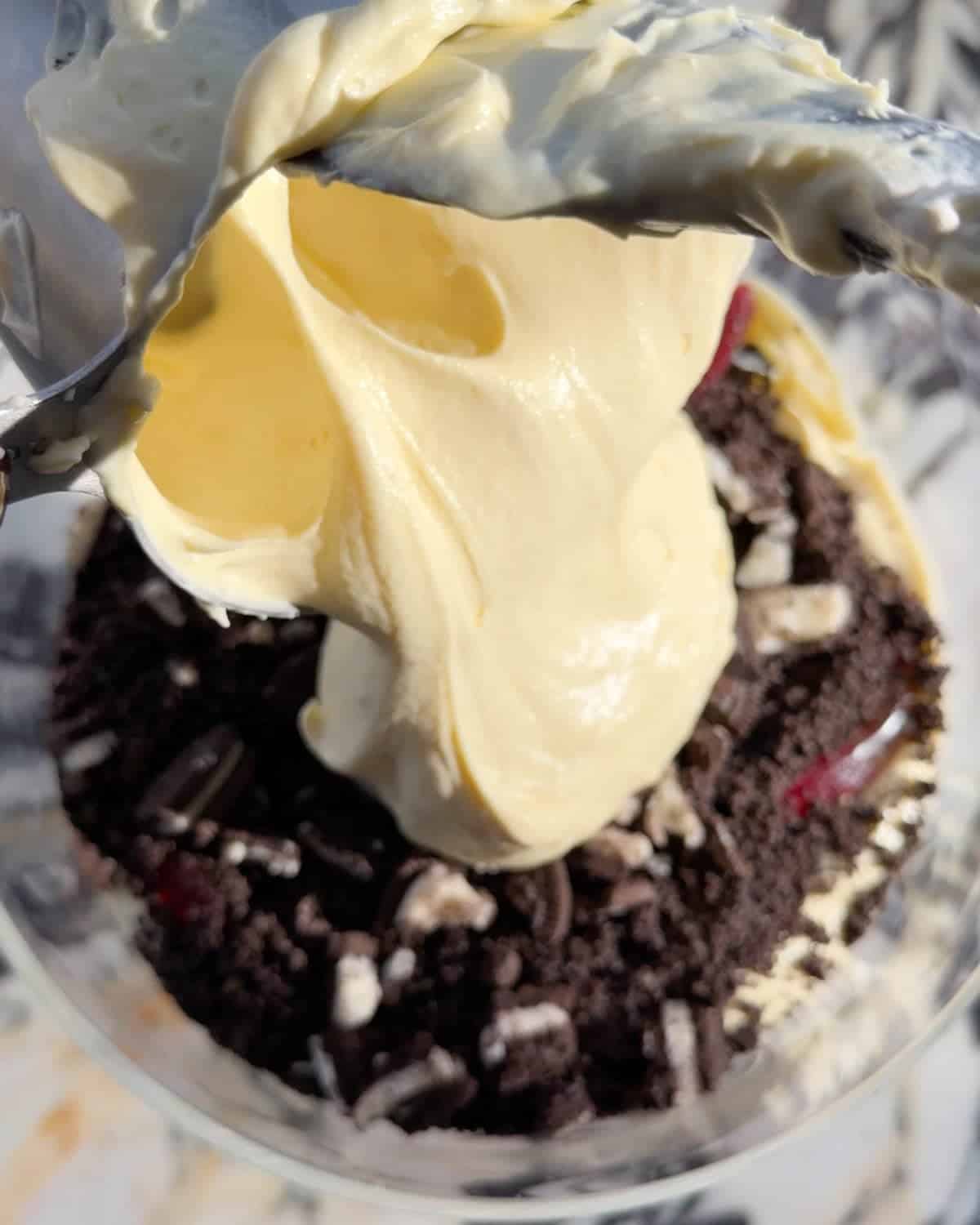 assembling this dirt cake recipe - overhead photo of the final pudding layer being added to the glass trifle dish on a marble surface