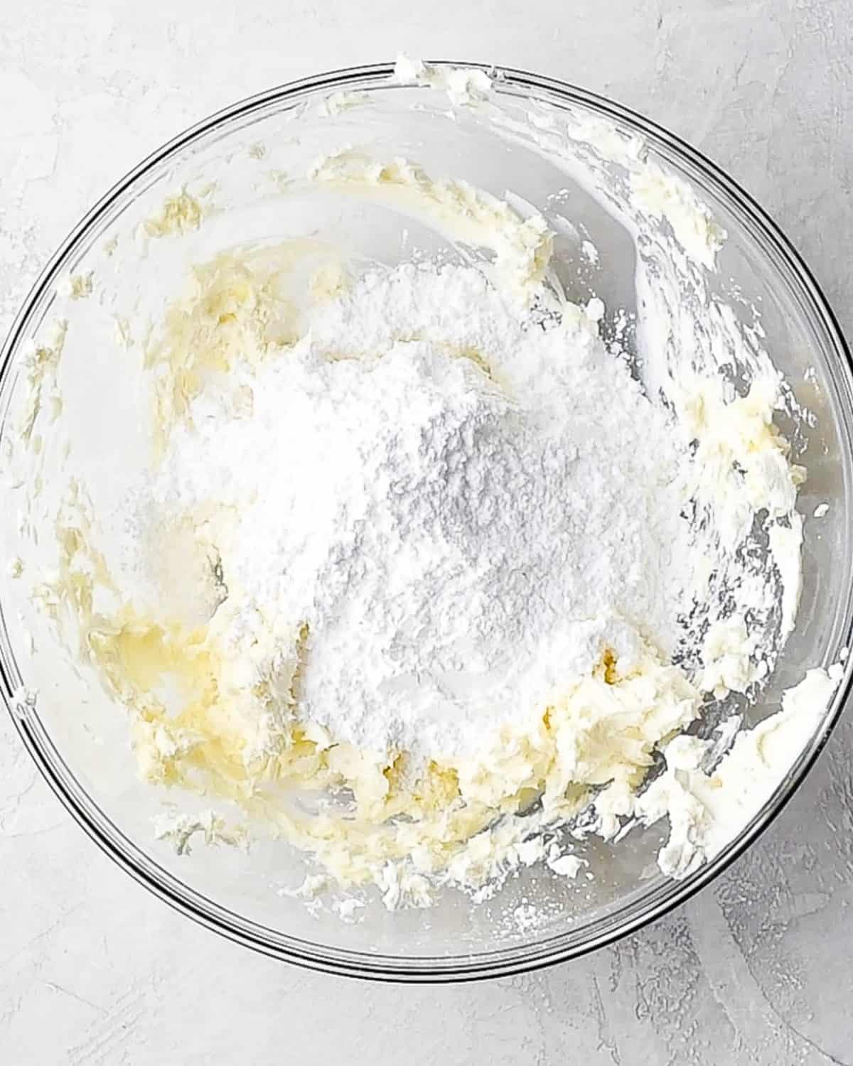 making oreo dirt cake recipe - powdered sugar added to the butter and cream cheese mixture before beating