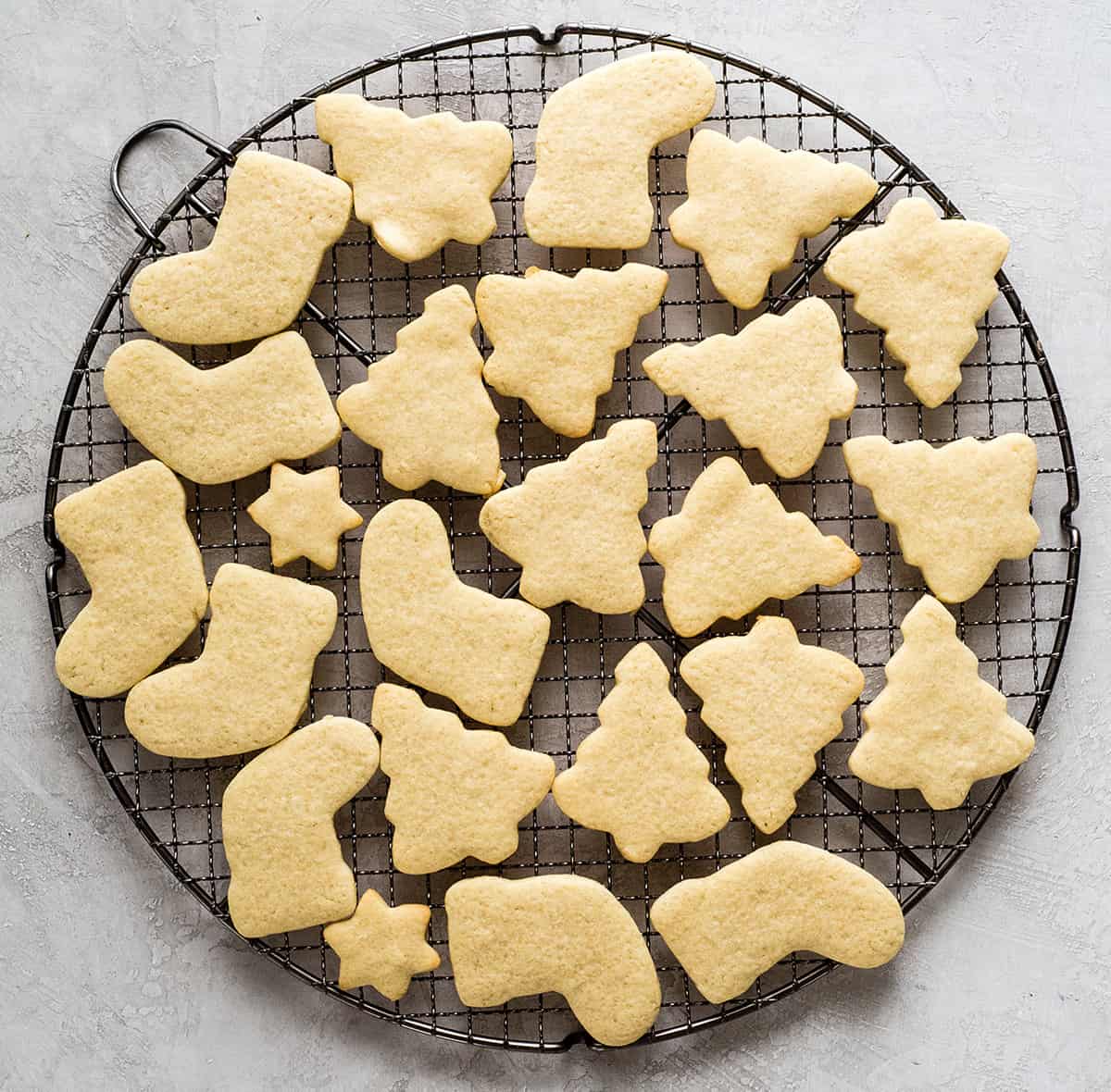 overhead photo of cut-out sugar cookies in Christmas shapes on a wire cooling rack