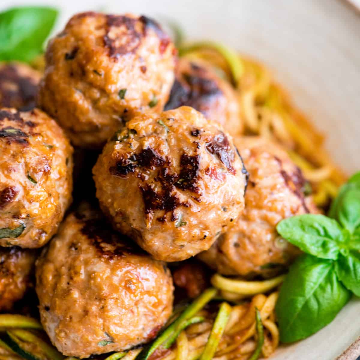 up close front view of six Healthy Turkey Meatballs in a bowl on top of zucchini noodles