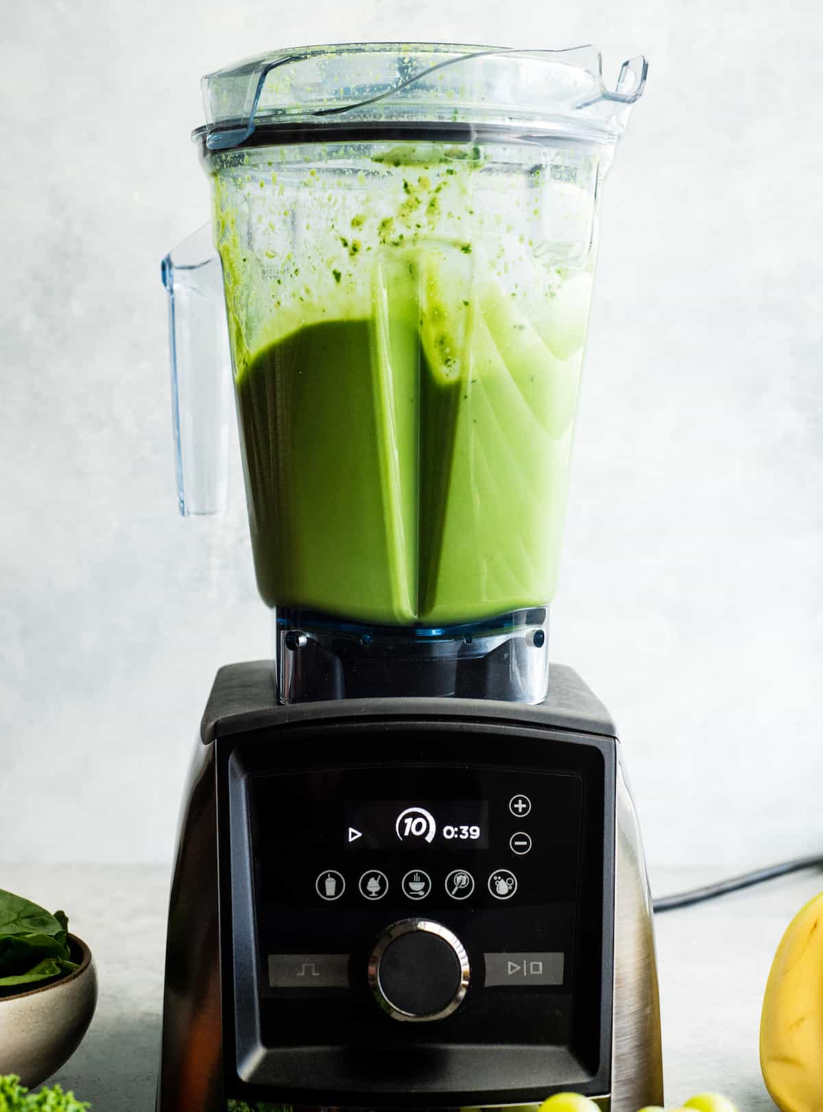 Front view of a Vitamix A3500 blender blending a green smoothie