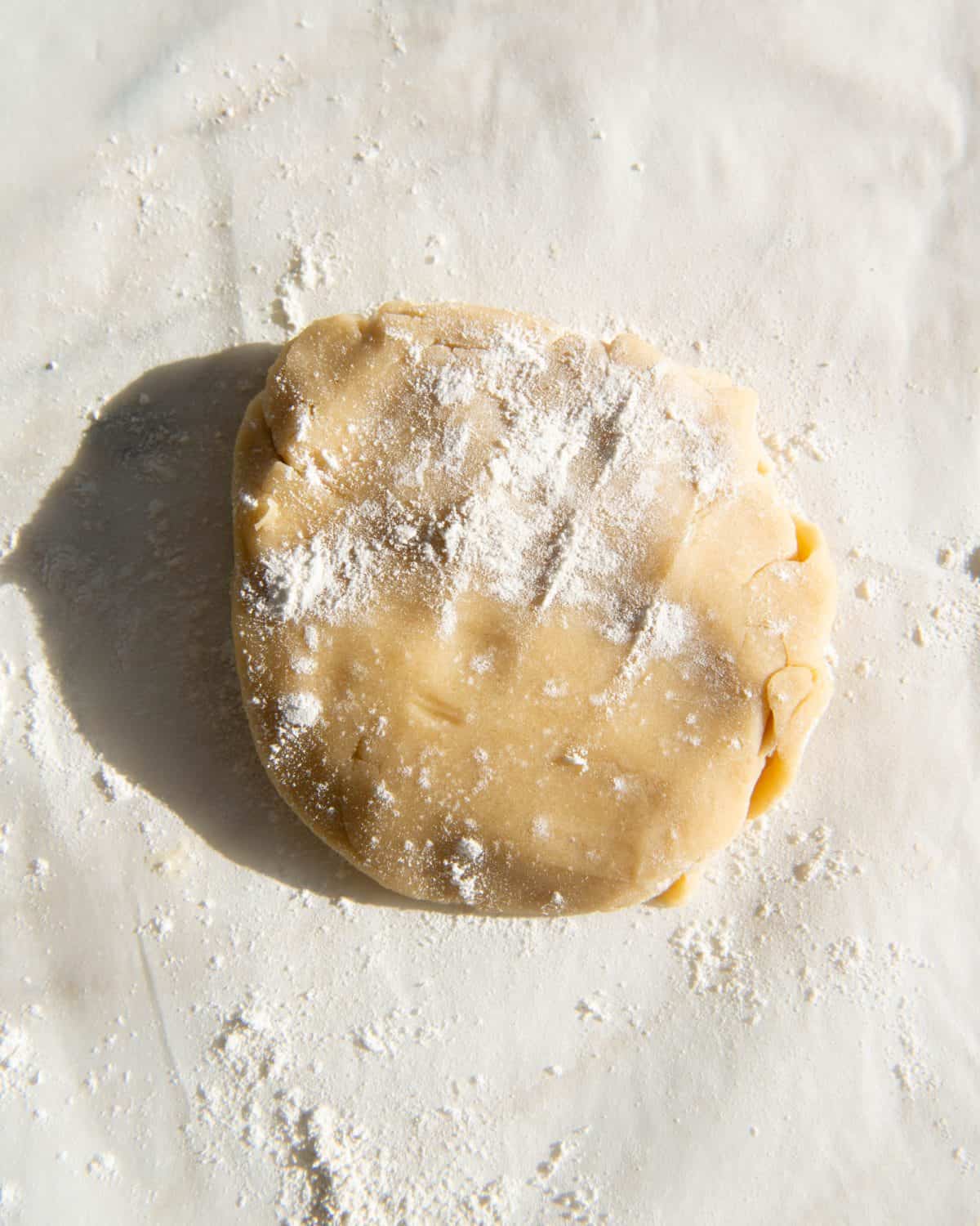 making sugar cookies recipe cut outs - dough scraps formed into a disc and covered in flour to be rolled again.